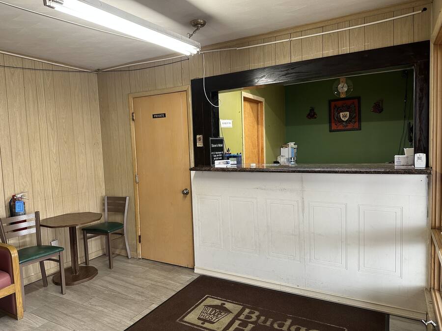 A reception area with a wooden door labeled "PRIVATE," a reception desk with a mirror, and a small table with chairs.