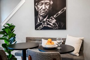 A modern interior with a grey sofa, two round tables, a plate of fruit, and a wine glass.