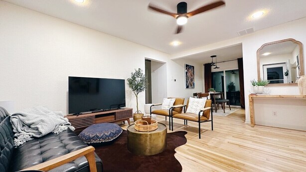 Ein modernes Wohnzimmer mit einer Couch, Sesseln, einem Couchtisch und einem Flachbildfernseher.