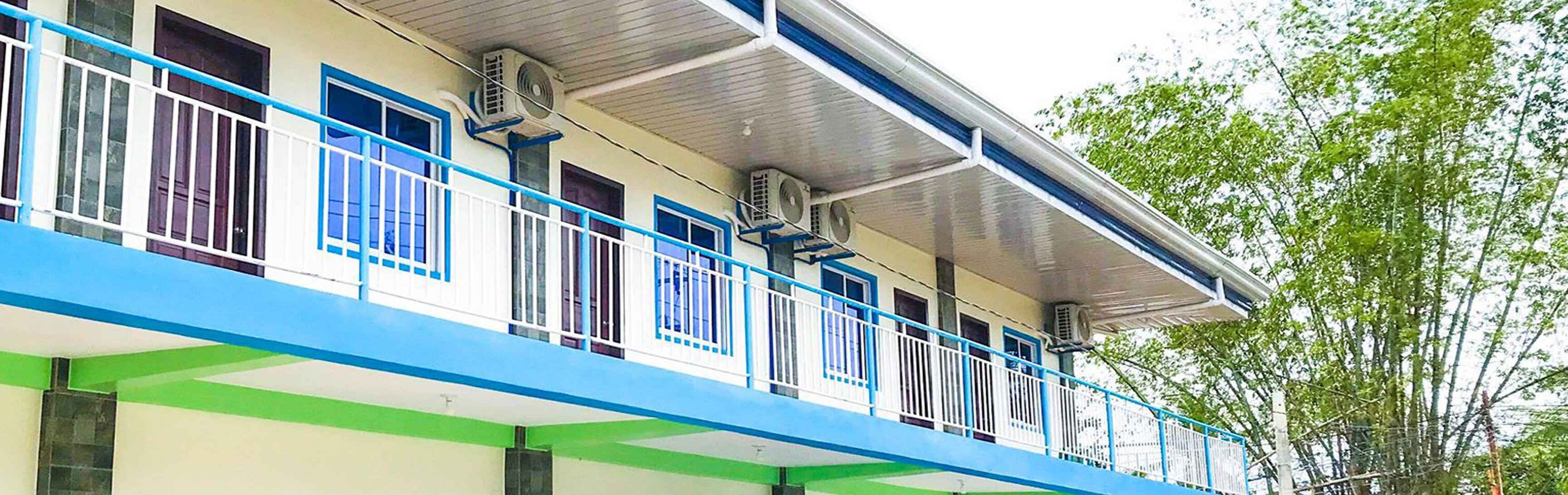 Ein mehrstöckiges Gebäude mit blau-weißer Fassade, ausgestattet mit Balkonen und Geländern sowie Klimaanlagen.