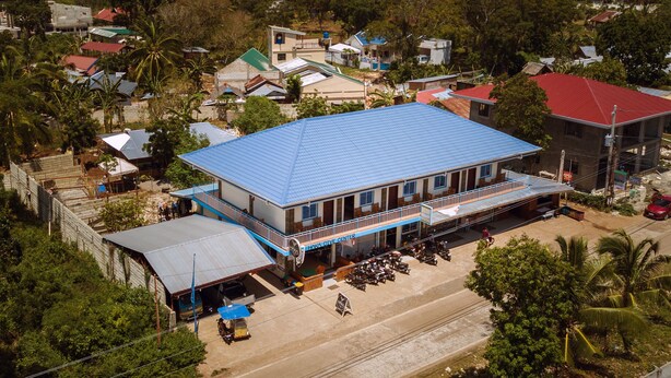 Un bâtiment à deux étages, avec un toit bleu, un porche avant couvert et une enseigne sur laquelle on peut lire : « Centre de plongée Haka ».