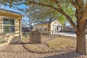 A residential property with a fenced yard, a wooden fence, and a tree. - Home Near Main St / 4BR / Hot Tub / Private Yard (Fredericksburg)