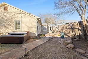 A residential property with a patio area, outdoor seating, and a wooden fence. - Home Near Main St / 4BR / Hot Tub / Private Yard (Fredericksburg)