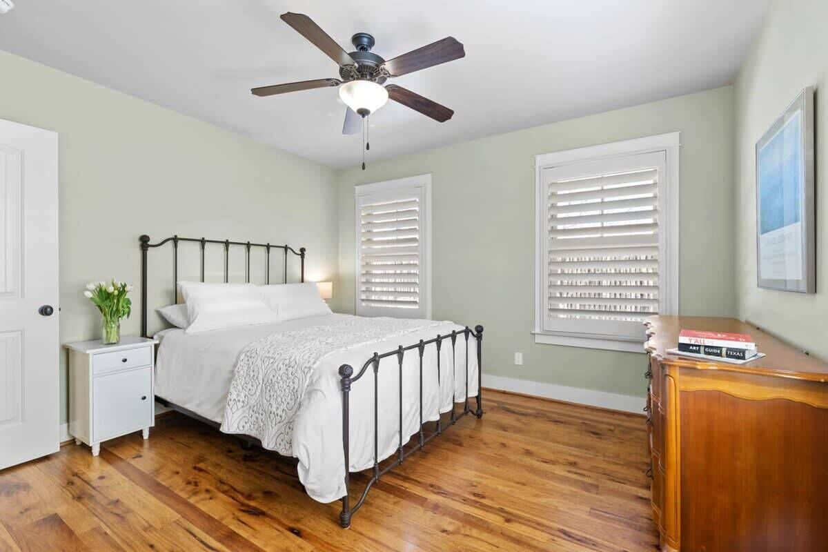 A bedroom with a bed, nightstand, dresser, and ceiling fan.