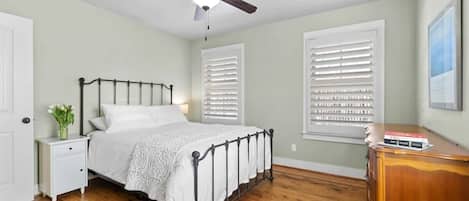 A bedroom with a bed, nightstand, dresser, and ceiling fan.