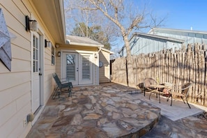 A stone patio with outdoor furniture, a wooden fence, and a house with siding.