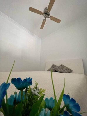 A bedroom with a ceiling fan, a bed with white bedding, and a pillow.