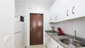 A kitchen with white cabinets, a granite countertop, a red coffee maker, and a stainless steel sink.