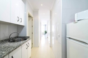A modern kitchen with white cabinets, a granite countertop, and a stainless steel sink.