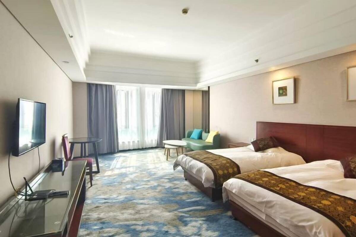 Een hotelkamer met twee bedden, een televisie, een bureau, een stoel en een klein tafeltje.