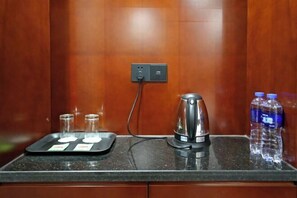 Eine Küchenarbeitsplatte mit einer Kaffeemaschine, zwei Gläsern, einer Serviertschale mit einer Karte und zwei Wasserflaschen.