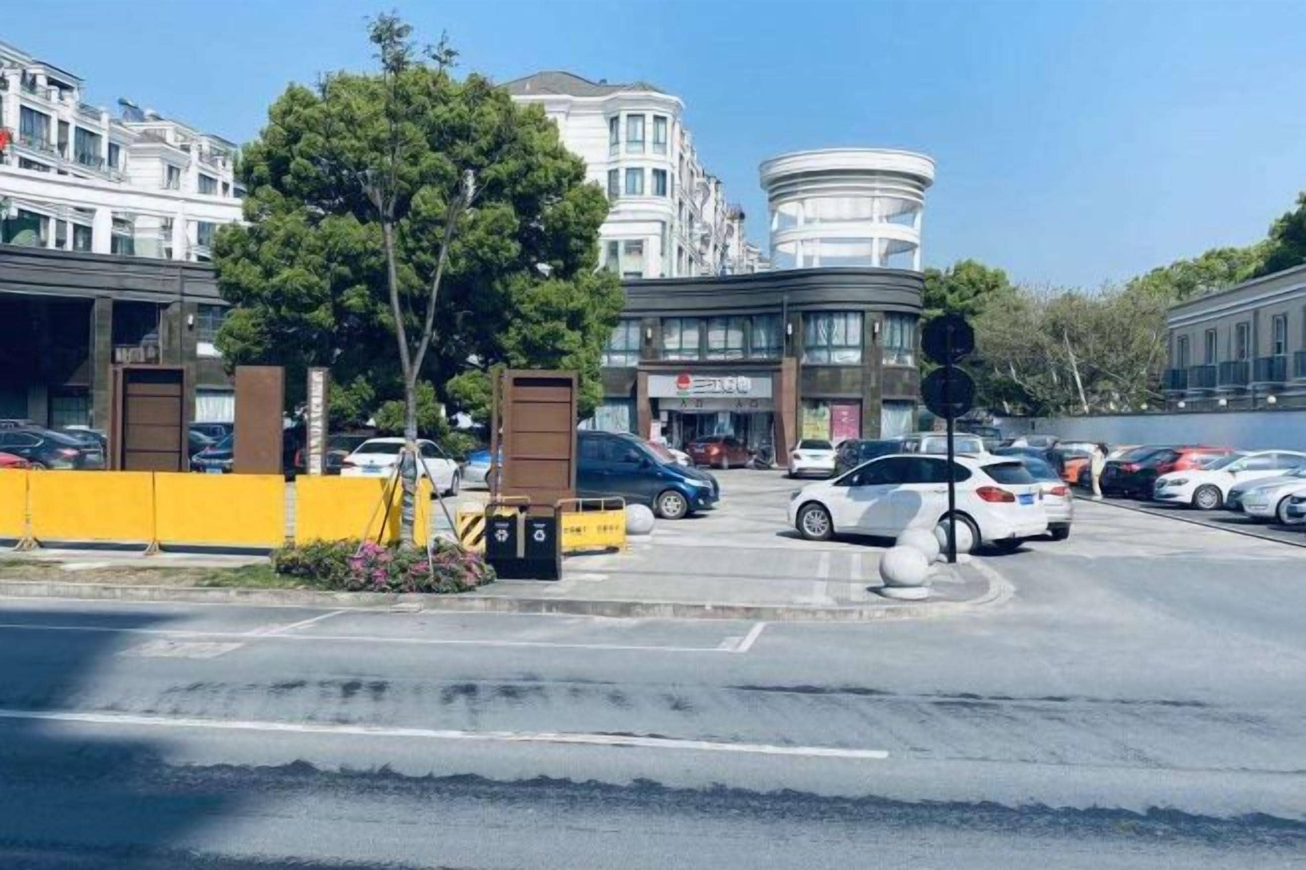 Un estacionamiento con coches, una barrera amarilla y edificios al fondo.