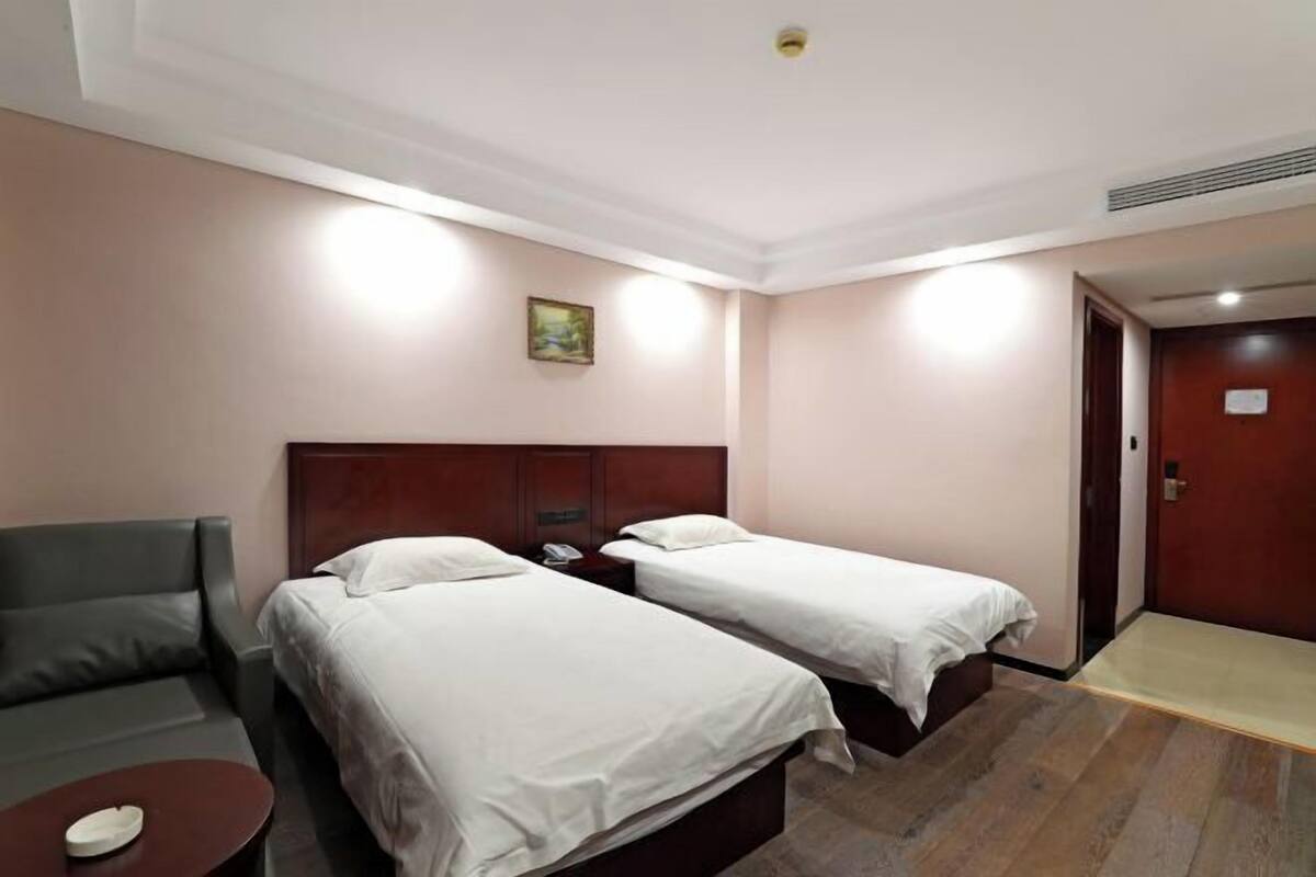 Een hotelkamer met twee bedden, een bank, een eettafel en een deur.