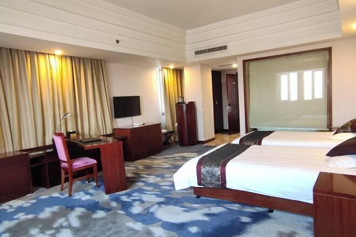 A hotel room with a bed, a desk, a chair, and a television.