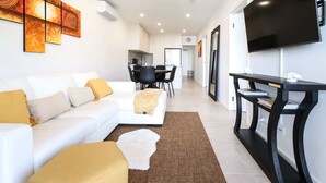 A modern living room with a white sofa, a coffee table, and a TV on a stand. - Glorious 2-Bed with Waterside Balcony Views (Batemans Bay)