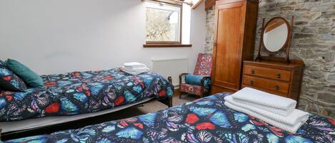 A bedroom with two beds, a wooden wardrobe, a chair, and a skylight.