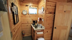 A compact wooden cabin with a kitchenette, a sink, a clock, and a door. - Westby House Lodge-Pinewood Room (Westby)