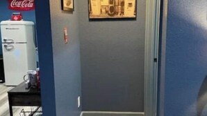A hallway with a Coca-Cola refrigerator, a framed picture on the wall, and a wooden floor. - Cozy Service Station in the heart of Staples (Martindale)