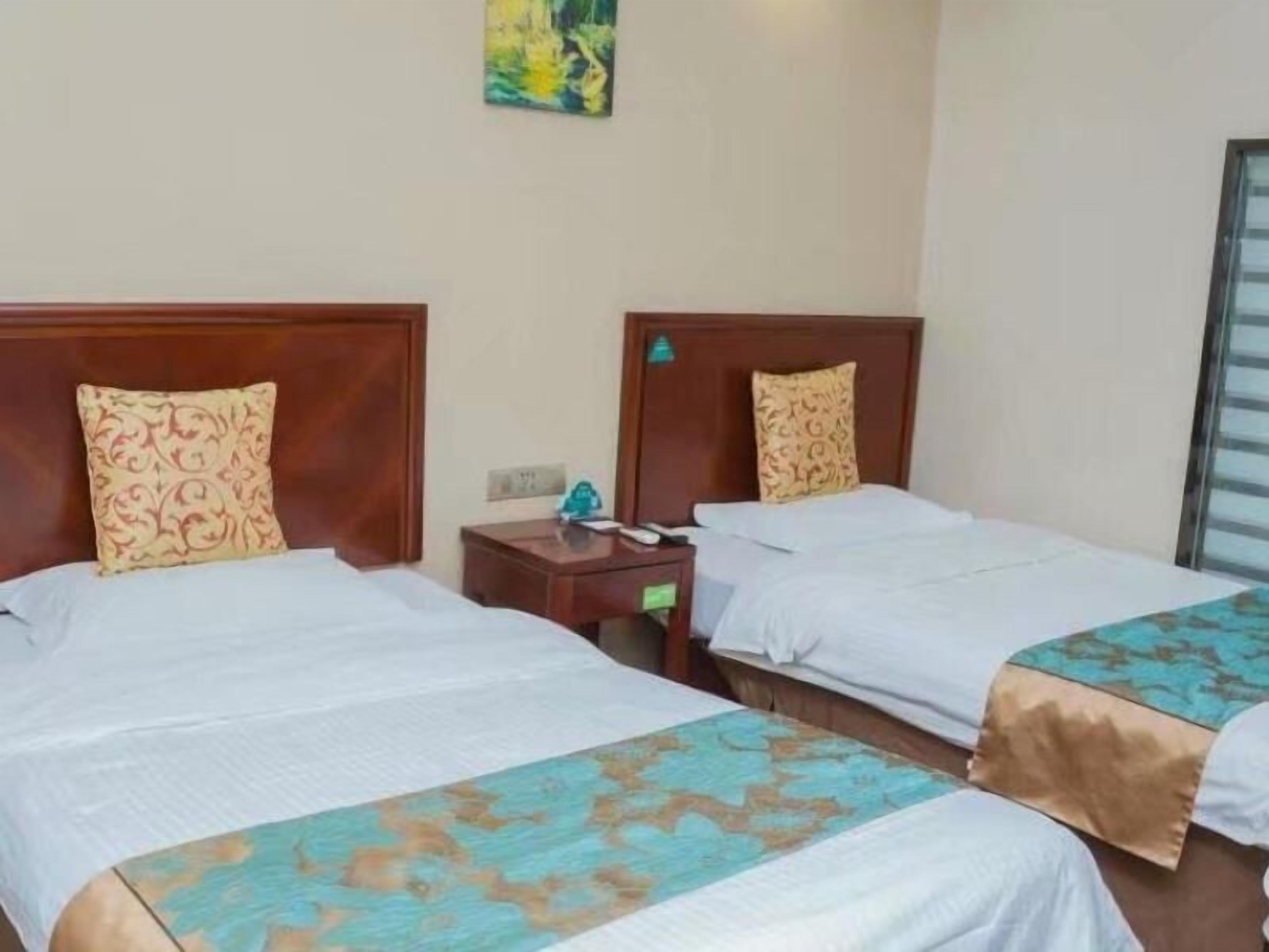 Habitación de hotel con dos camas, cada una con cabecero de madera y almohadas decorativas a juego.