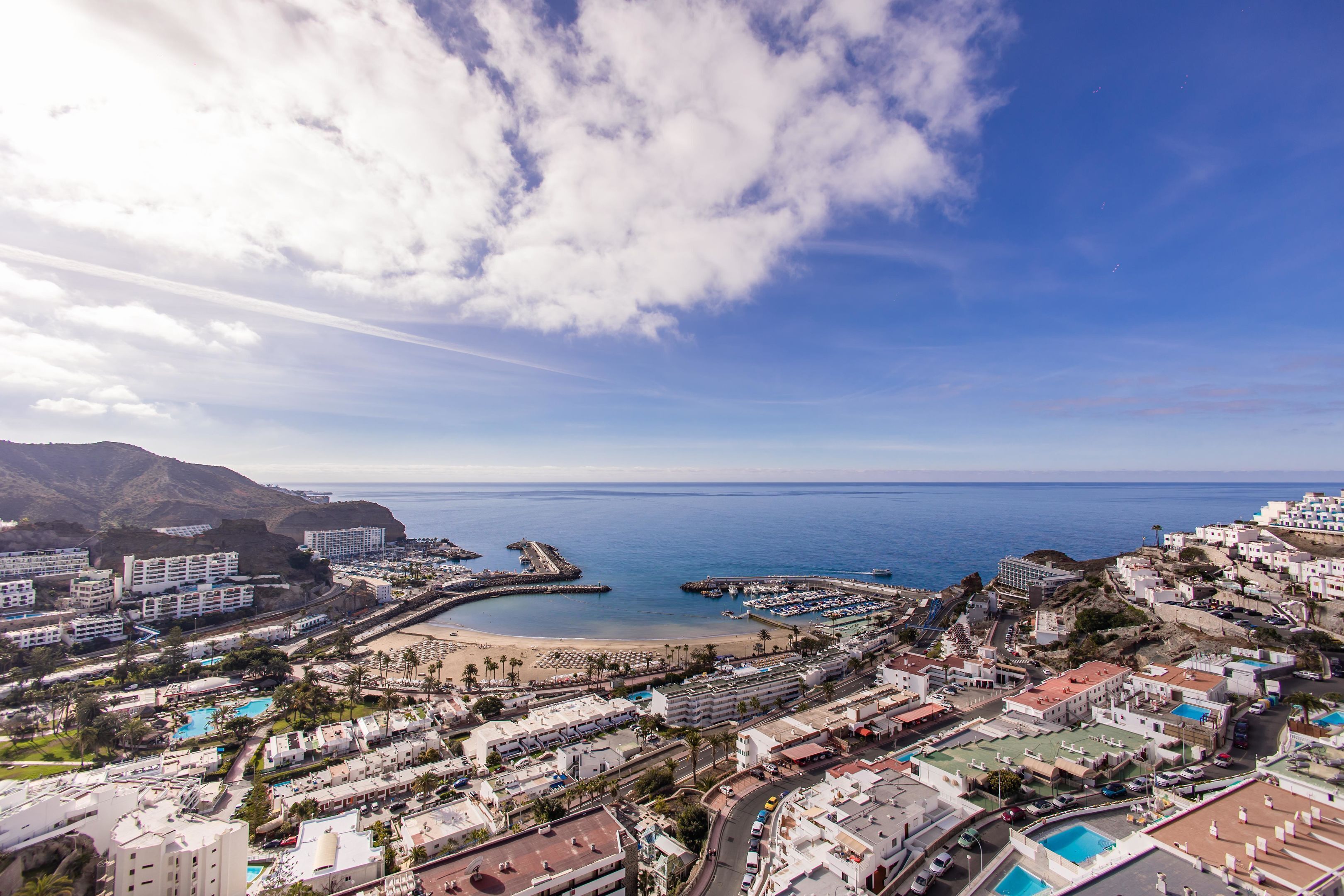 A coastal town with a beach, marina, and residential buildings.