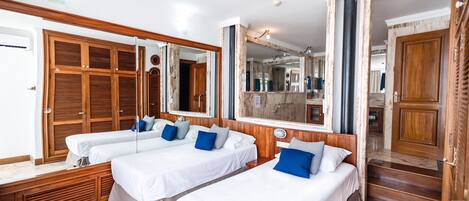 Une chambre d’hôtel avec deux lits simples, des armoires en bois, un grand miroir et un sol en marbre.