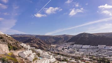 Un pueblo costero con edificios blancos, piscina y montañas al fondo.