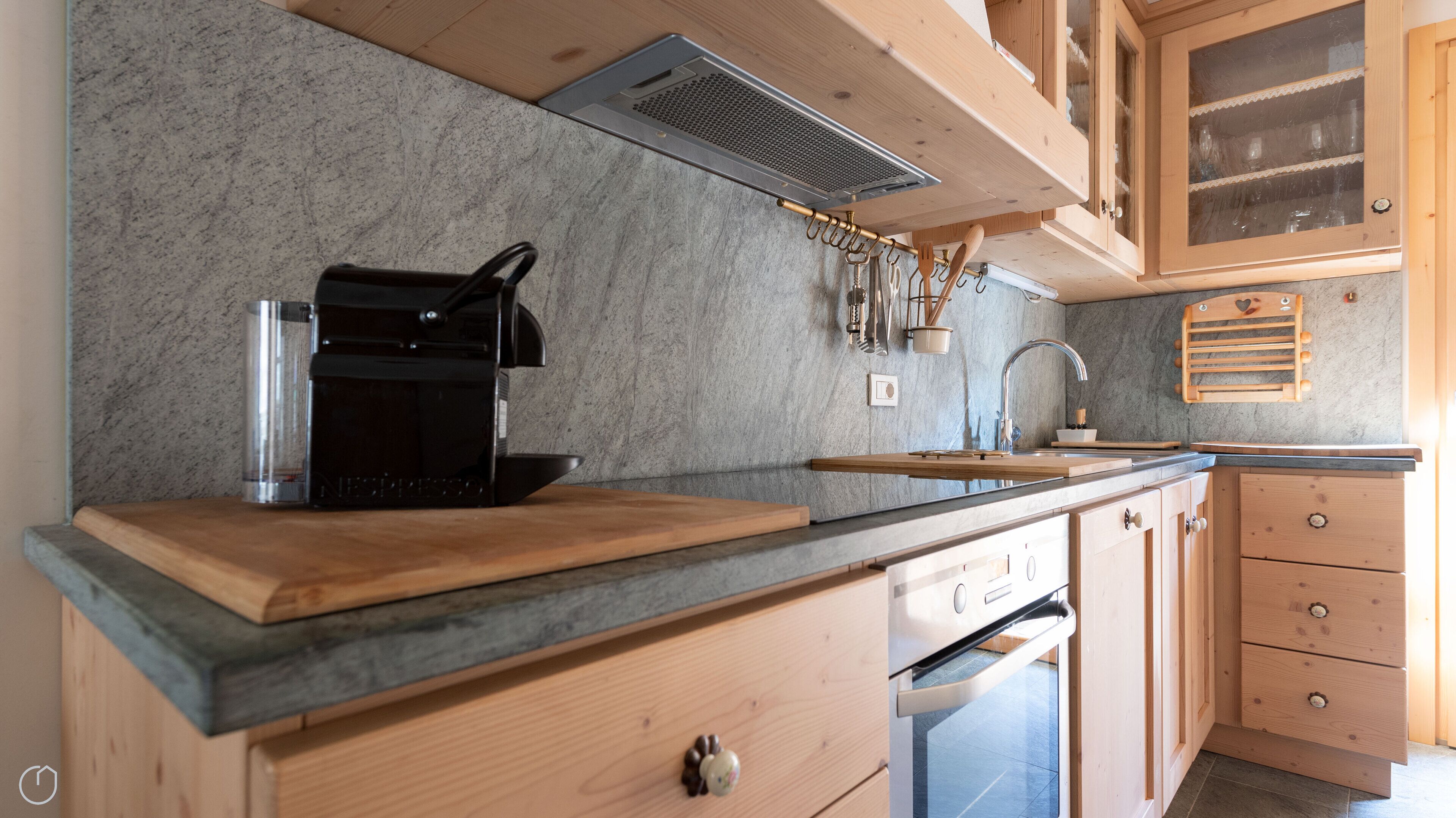 A modern kitchen with a built-in espresso machine, wooden cabinets, and a granite countertop.