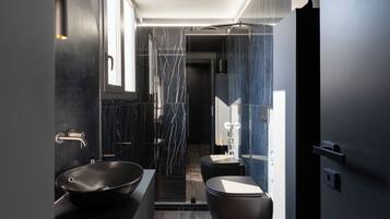 Un bany modern amb un lavabo negre de disseny, una dutxa a nivell i un vàter.