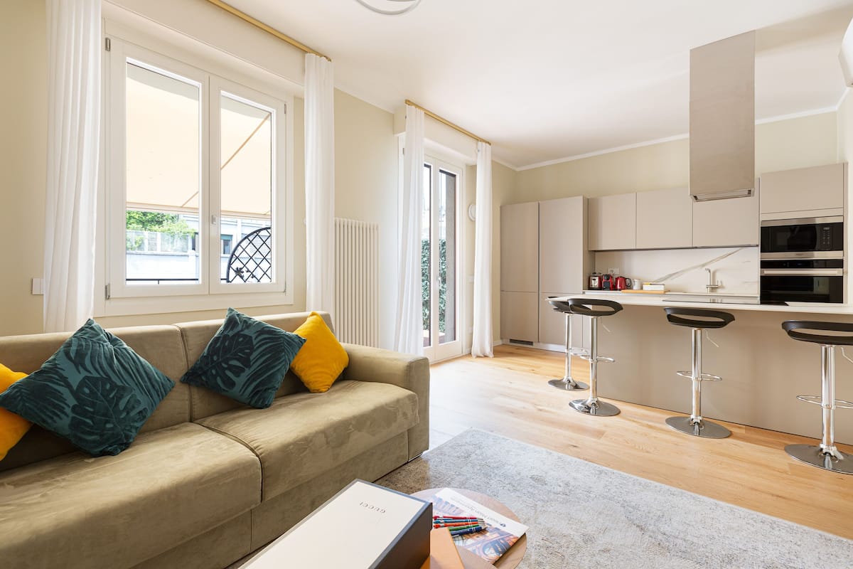 Un apartamento moderno con sala de estar que incluye un sofá, una mesa de centro y una cocina con barra.