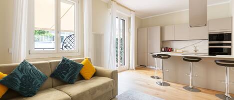 A modern apartment with a living area featuring a sofa, a coffee table, and a kitchen with a bar area.