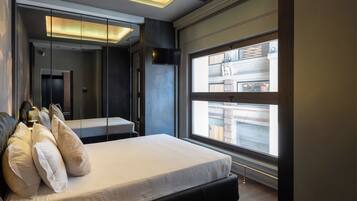 Un dormitorio moderno con una cama grande, un espejo y una ventana con vistas a un edificio.