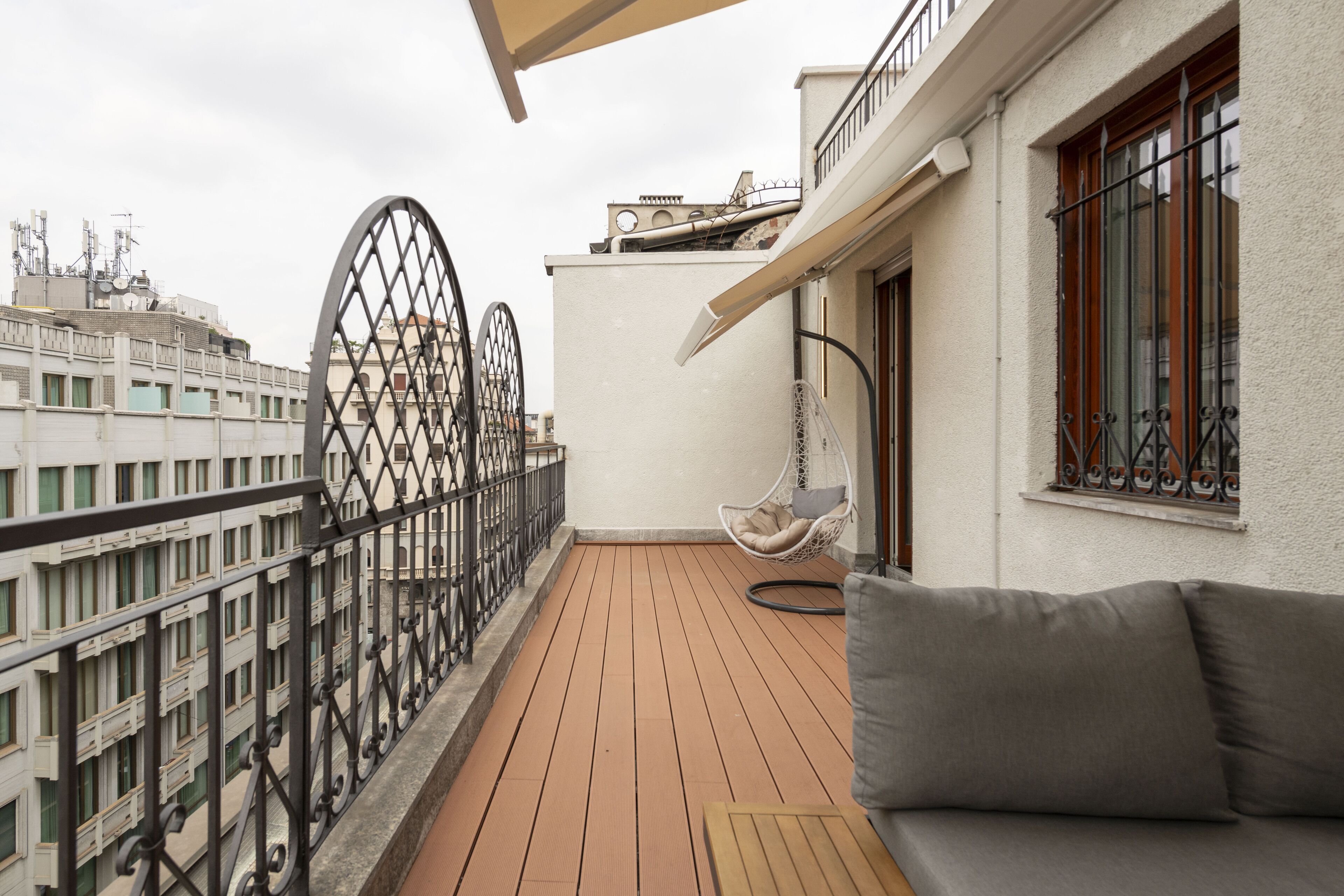 Ein Balkon mit Holzboden, einem Hängesessel und einer Couch.