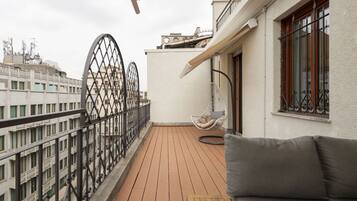 Un balcone con pavimento in legno, una sedia a dondolo e un divano.
