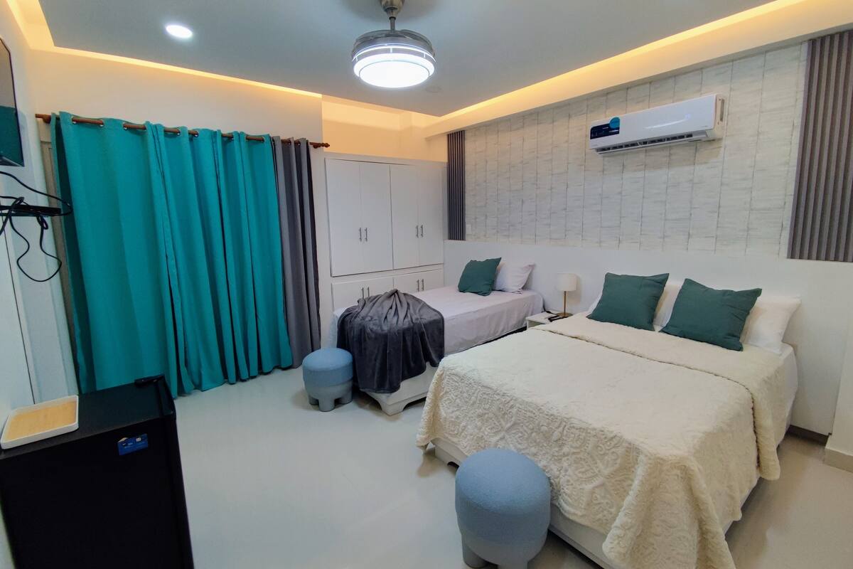 Une chambre moderne comprenant un lit, des tables de chevet, une armoire, un climatiseur et un ventilateur de plafond.