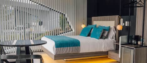 A modern bedroom with a bed, bedside tables, a desk, and a chair.