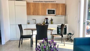 A kitchenette with a microwave, a dining table with chairs, and a vase of purple flowers. - Apartment 2 minutes from Ruppione beach (Pietrosella)