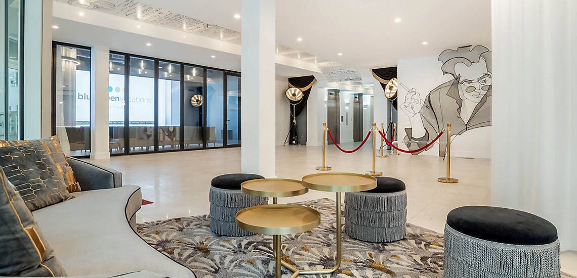 A modern lobby with seating, a reception desk, and a large wall mural.