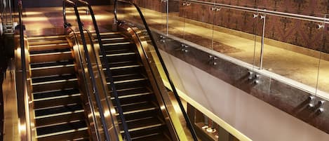 An escalator in a hotel lobby with a patterned wall and framed artwork.