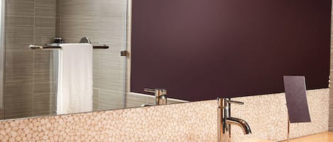 A modern bathroom with a large mirror, a bathtub, and a sink.