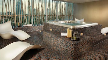 Relax in a serene spa area with a large hot tub, mosaic-tiled floor, and comfortable seating.