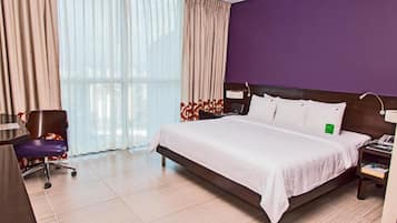 A hotel room with a bed, a desk, a chair, and a nightstand.
