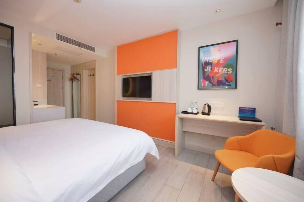 Una habitación de hotel con una cama, un escritorio, una silla, un televisor y un cartel en la pared.