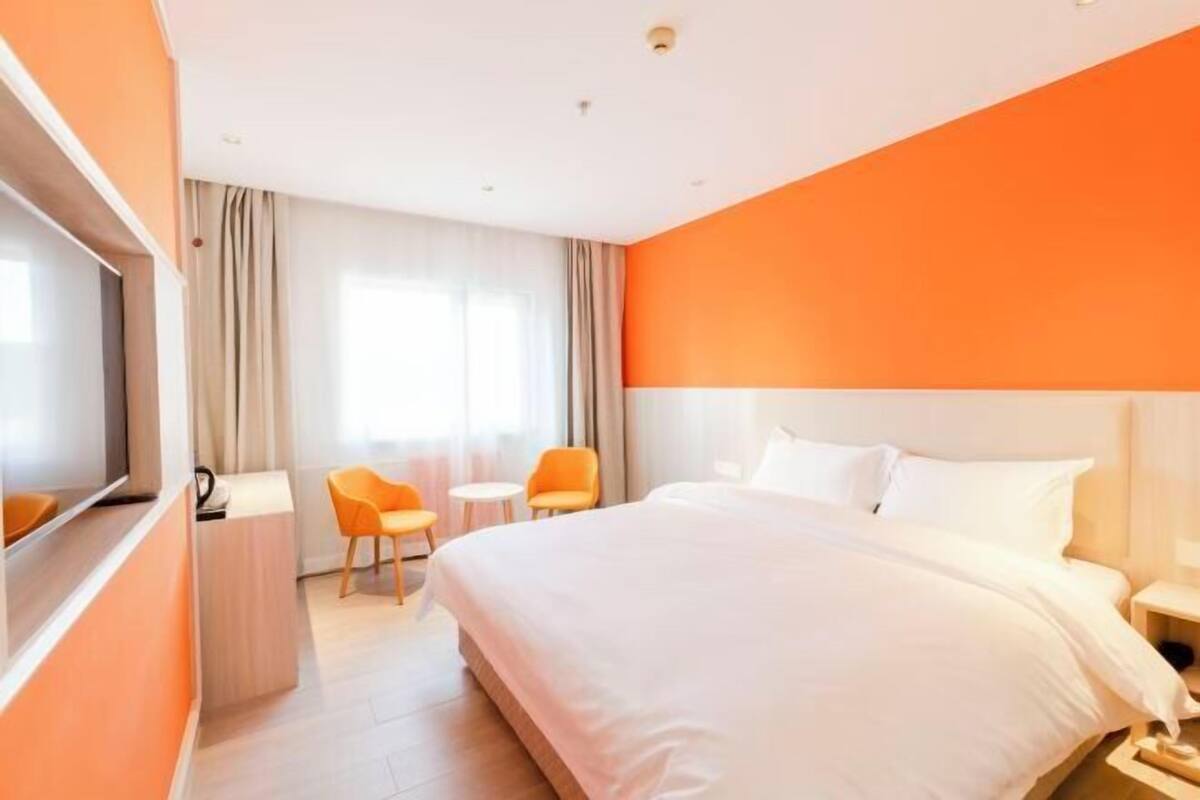 Una habitación de hotel con una cama grande, televisión, escritorio y dos sillas.