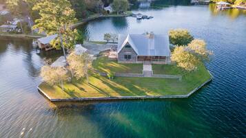 Un chalet au bord du lac, doté d’un quai, entouré d’arbres et offrant une vue dégagée sur le lac.