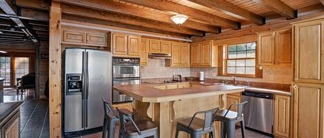 A spacious kitchen with wooden cabinets, stainless steel appliances, and a central island with bar stools.