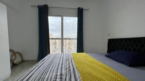 A bedroom with a bed, a window with curtains, and a balcony view. - Alrehab city luxury apartment (Cairo Governorate)