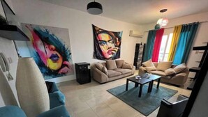 A living room with two sofas, a coffee table, and a painting on the wall. - Alrehab city luxury apartment (Cairo Governorate)