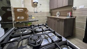 A kitchen with a gas stove, a water heater, and wooden cabinets. - Alrehab city luxury apartment (Cairo Governorate)