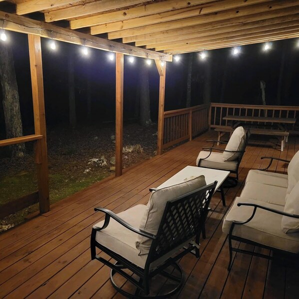Un patio in legno con posti a sedere all'aperto e luci a stringa.