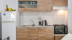 Eine kleine Küche mit Holzschränken, einem weißen Kühlschrank, einer Mikrowelle und einem Spülbecken.